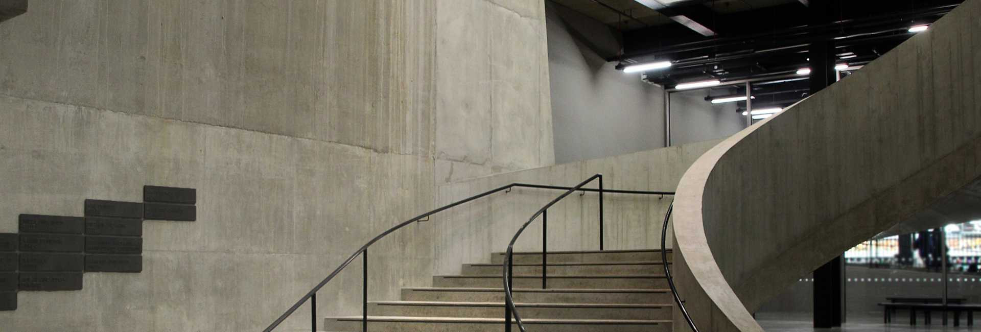 Gewundene Betontreppe führ nach oben.